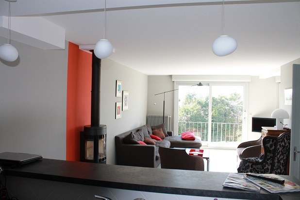 Séjour avec mur orange peint et poêle à bois